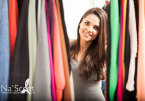 Portrait of a pretty young woman looking through some of her clothes in a wardrobe ans smiling